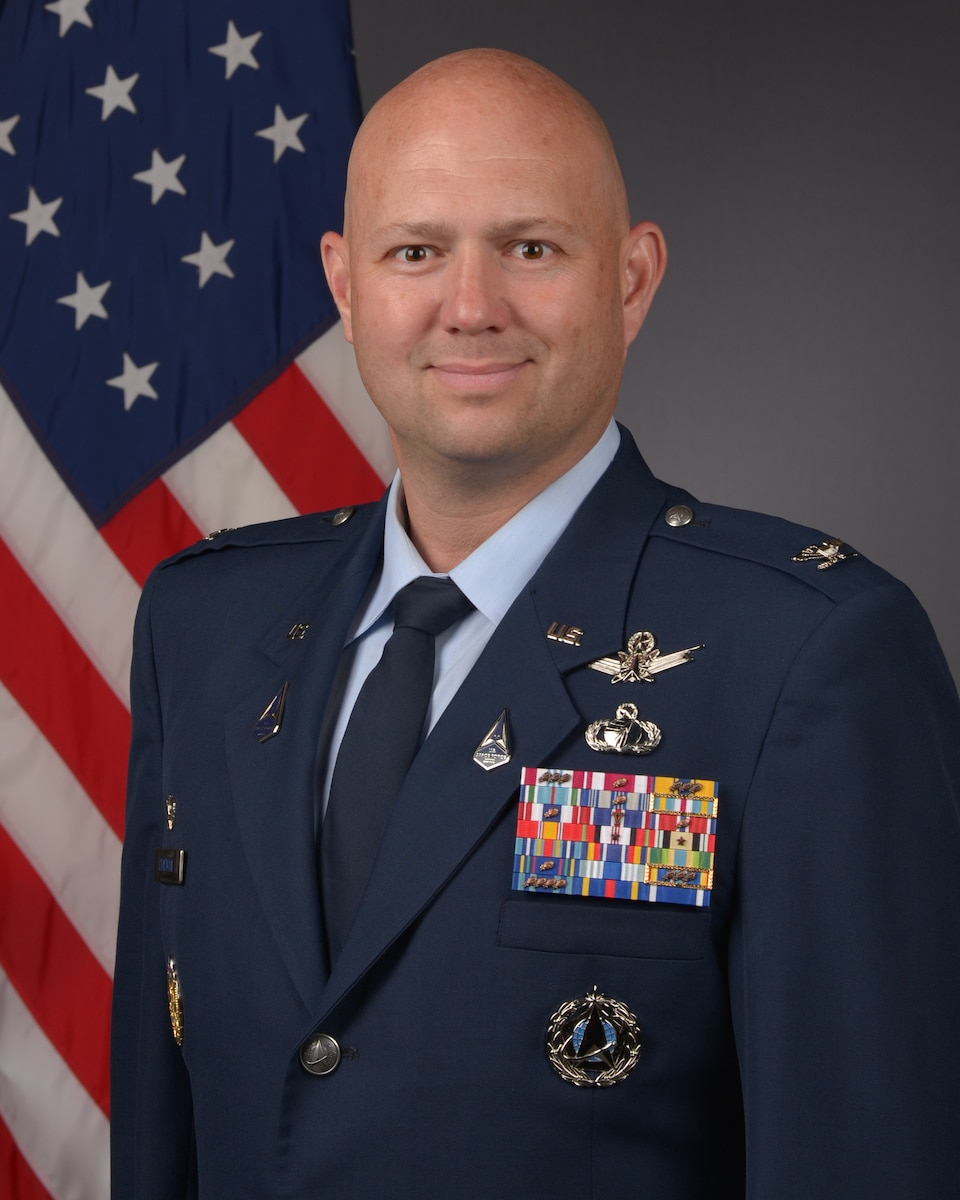 Man standing in front of gray background with American flag in Space Force military dress uniform