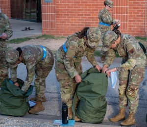 315th Training Squadron enlisted and officer members participate in the bag-drag exercise in front of their campus as part of a mock deployment held at Goodfellow Air Force Base, Texas, June 25th. Officer-enlisted integration remains a focus of the 315th Training Squadron, as it helps build mutual trust ahead of the final capstone project, which is a highly collaborative, team-based event.  (U.S. Air Force photo by Airman 1st Class James Salellas)