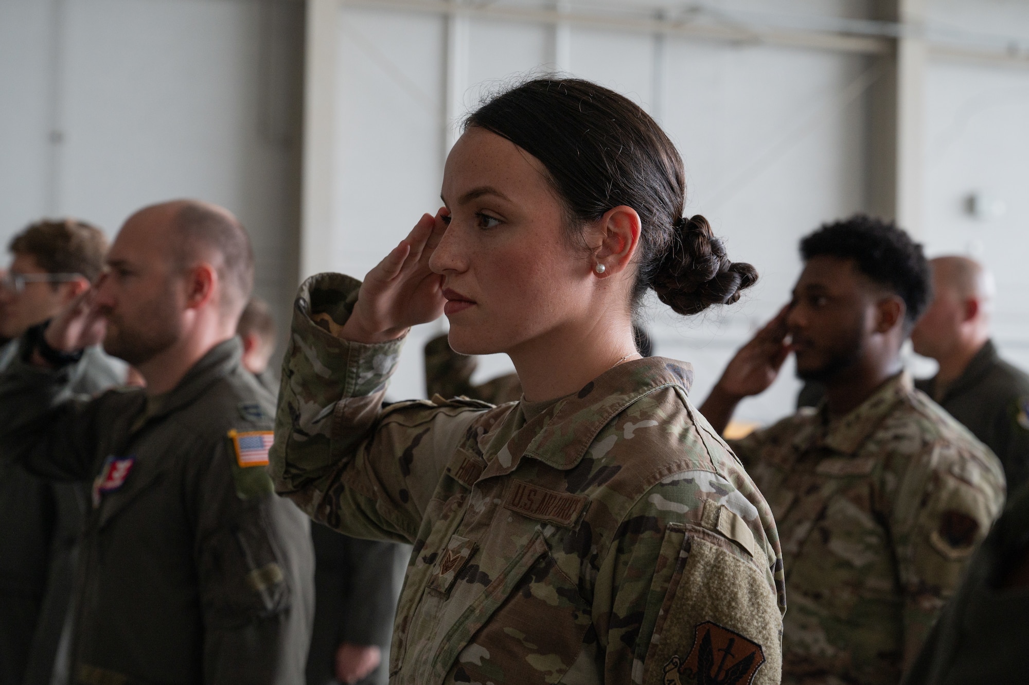 An airman saluting with a group of people behind her.