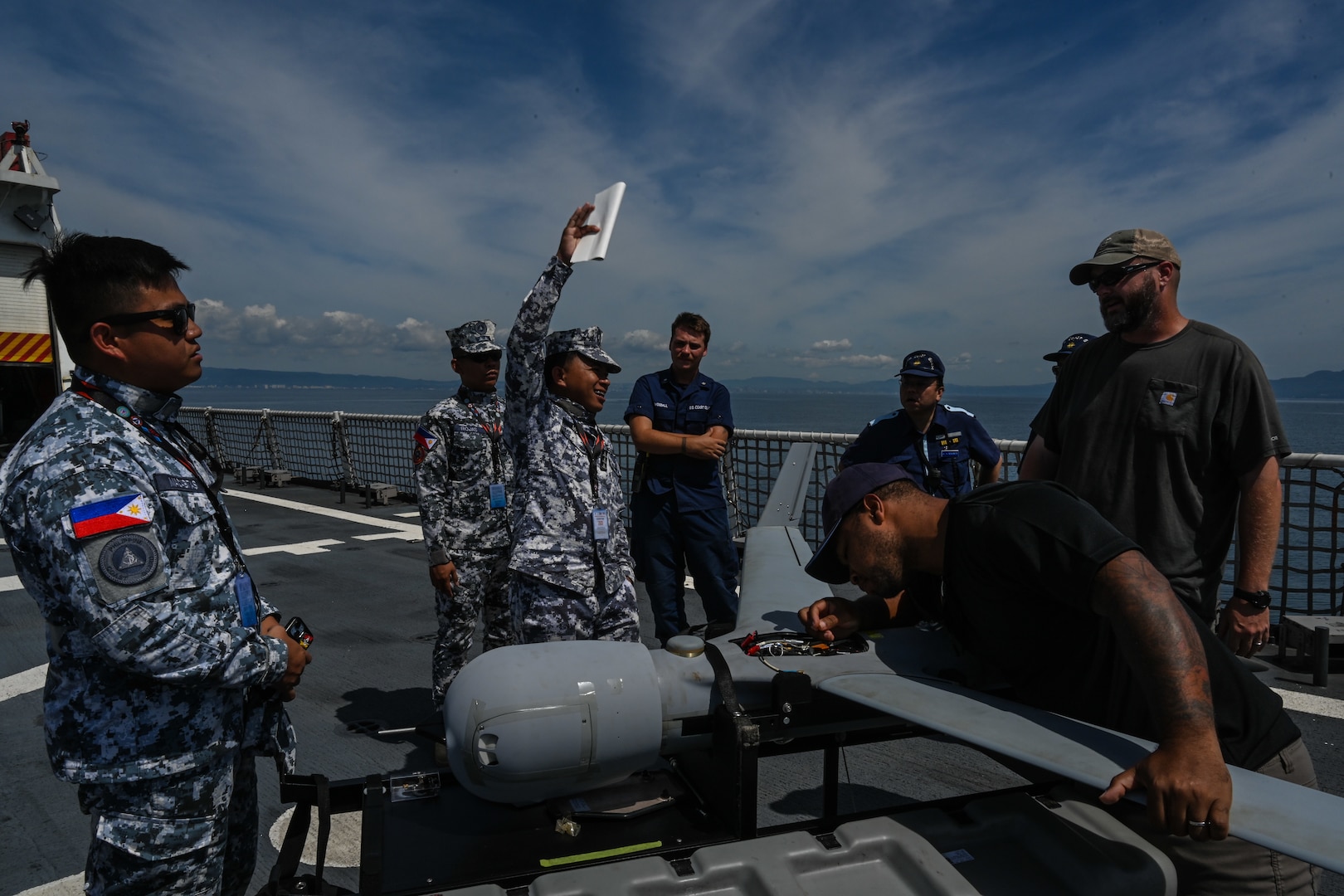 Philippine and Japan Coast Guard members observe a ScanEagle long-endurance unmanned aerial system aboard the Legend-class U.S. Coast Guard Cutter Stratton (WMSL 752) during a trilateral search and rescue exercise in Kagoshima, Japan, June 20, 2025. Stratton is deployed and assigned to Destroyer Squadron (DESRON) 15, the Navy’s largest DESRON and the U.S. 7th Fleet’s principal surface force. Stratton is deployed to the Indo-Pacific to advance relationships with ally and partner nations to build a more secure and prosperous region with unrestricted, lawful access to the maritime commons. (U.S. Coast Guard photo by Petty Officer 2nd Class Kate Kilroy)