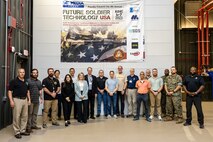 Army and Marine Corps representatives, along with industry partners, in a group photo in front of a Future Soldier banner