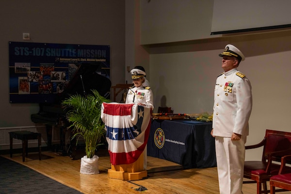 250616-N-JC800-1081 BETHESDA, Md. (June 12, 2025) - Capt, Katharine Shobe, commanding officer of Naval Medical Leader and pProfessional Development Command, reads her orders during NMLPDC's Change of Command Ceremony, Jun. 12. (U.S. Navy photo by Mass Communication Specialist 1st Class Heath Zeigler/Released)