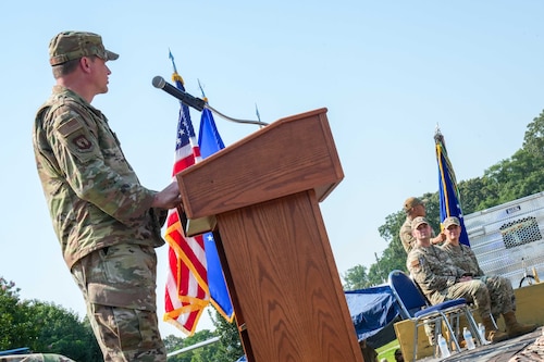 An Air Force commander gives a speech from behind a podium as two other commanders watch on.