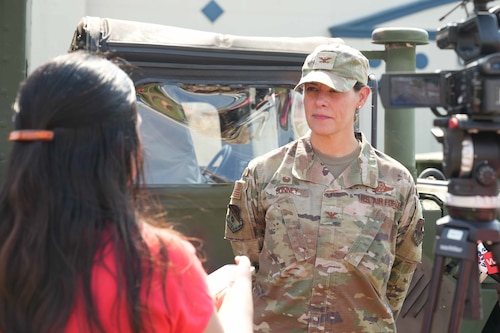 An Air Force commander speaks to a reporter with a camera next to her.
