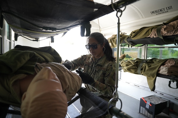 Senior Airman Grace Takemoto, aeromedical space technician, March Air Force Base, checks the blood pressure of a simulated casualty aboard an ambulance bus during a joint-service integrated medical training event at Camp Pendleton, California, May 12, 2025. The evolution was part of a larger Expeditionary Medical Facility (EMF) exercise conducted by Naval Expeditionary Medical Warfighter Development Center (NEMWDC) to enhance patient transport procedures and interoperability between Air Force and Navy medical teams. (U.S. Navy photo by Petty Officer 2nd Class Moira Esquivel)