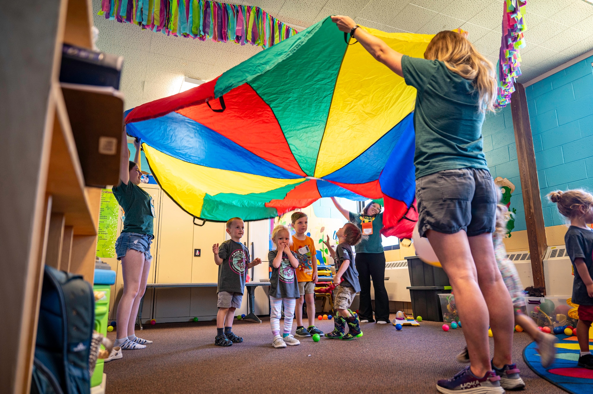 Children play under a colored parachute
