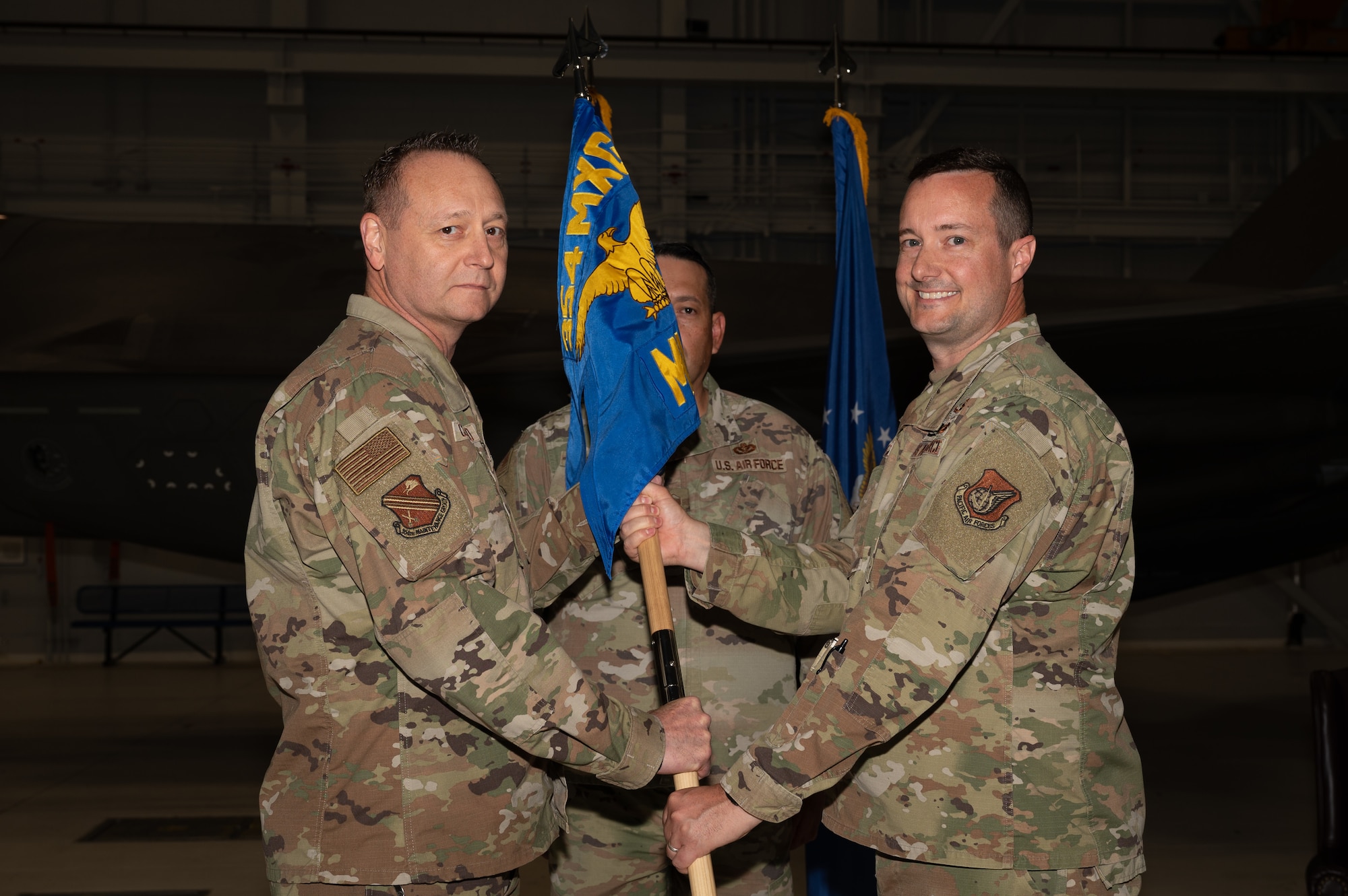 U.S. Air Force Maj. Jason Forcey, right, 354th Munitions Squadron outgoing commander, relinquishes the guidon to Col. Jerry Copeland, 354th Maintenance Group commander, during a change of command ceremony at Eielson Air Force Base, Alaska, June 26, 2025.