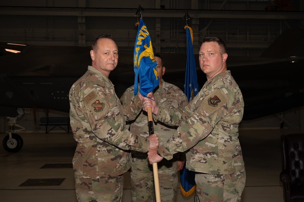 U.S. Air Force Col. Jerry Copeland, 354th Maintenance Group commander, passes the guidon to Maj. Garrett Evans, 354th Munitions Squadron incoming commander, during a change of command ceremony at Eielson Air Force Base, Alaska, June 26, 2025.