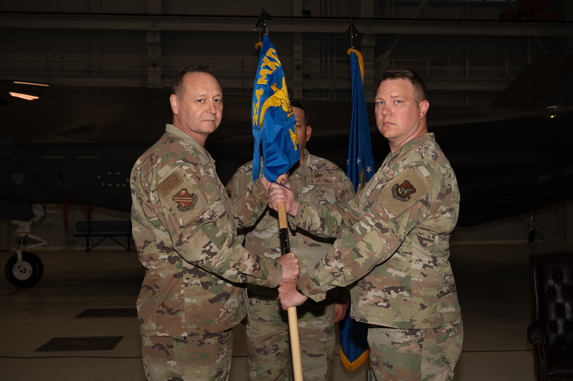 U.S. Air Force Col. Jerry Copeland, 354th Maintenance Group commander, passes the guidon to Maj. Garrett Evans, 354th Munitions Squadron incoming commander, during a change of command ceremony at Eielson Air Force Base, Alaska, June 26, 2025.