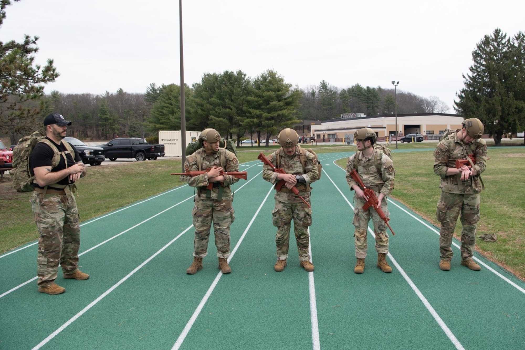 5 Air Force members stand on a track preparing to conduct a ruck.
