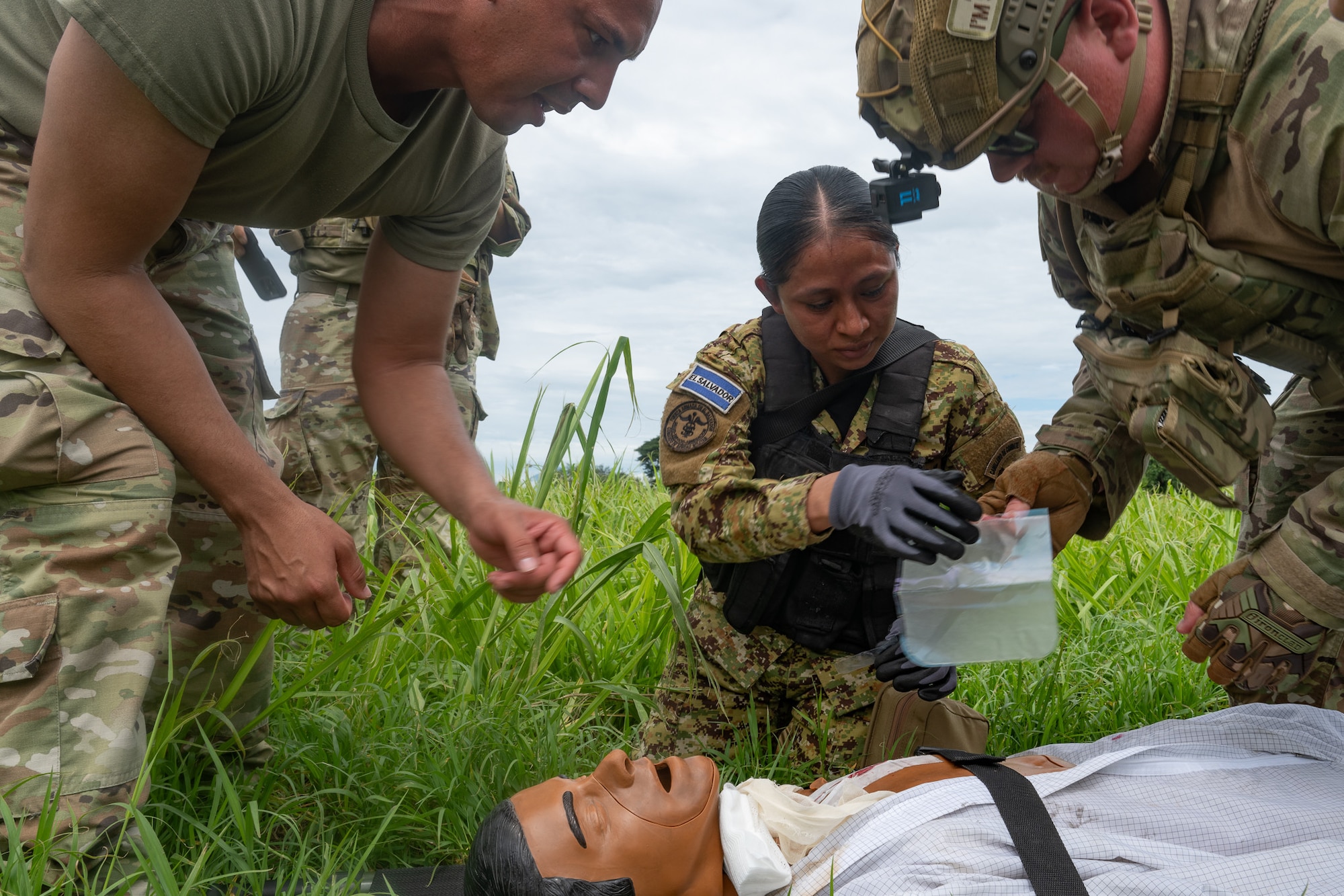 U.S. Air Force Tech. Sgt. John Nazario (left), 302d Aeromedical Staging Squadron medical technician, and Capt. Samuel Hendricks, 944th Aeromedical Staging Squadron critical nurse, assist an El Salvador Primera Brigada Aérea member with applying a seal to a sucking chest wound to a medical training mannequin in Ilopango, El Salvador, June 20, 2025. The training was part of the AMISTAD campaign, a mission designed to promote cooperation between U.S. and host nation medical professions training in resource-constrained environments. (U.S. Air Force photo by Tech. Sgt. Justin Norton)
