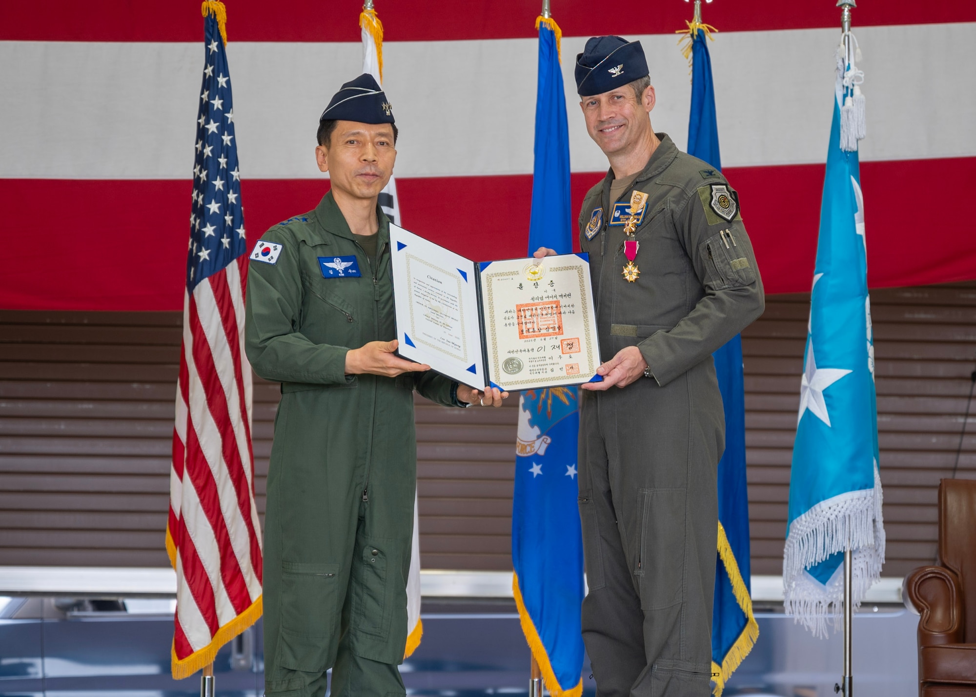 U.S. Air Force Col. William McKibban, right, outgoing 51st Fighter Wing commander,  receives the Order of National Security Merit Samil Medal from Republic of Korea Air Force Lt. Gen. Kim Hyoung Soo, left, ROKAF Operations Command commander,  during a Change of Command ceremony at Osan Air Base, Republic of Korea, June 27, 2025. The 51st FW is the most forward deployed permanently-based wing in the U.S. Air Force, providing combat-ready Airmen and aircraft to execute military operations and maintain stability across the Indo-Pacific region. (U.S. Air Force photo by Staff Sgt. Sarah Williams)
