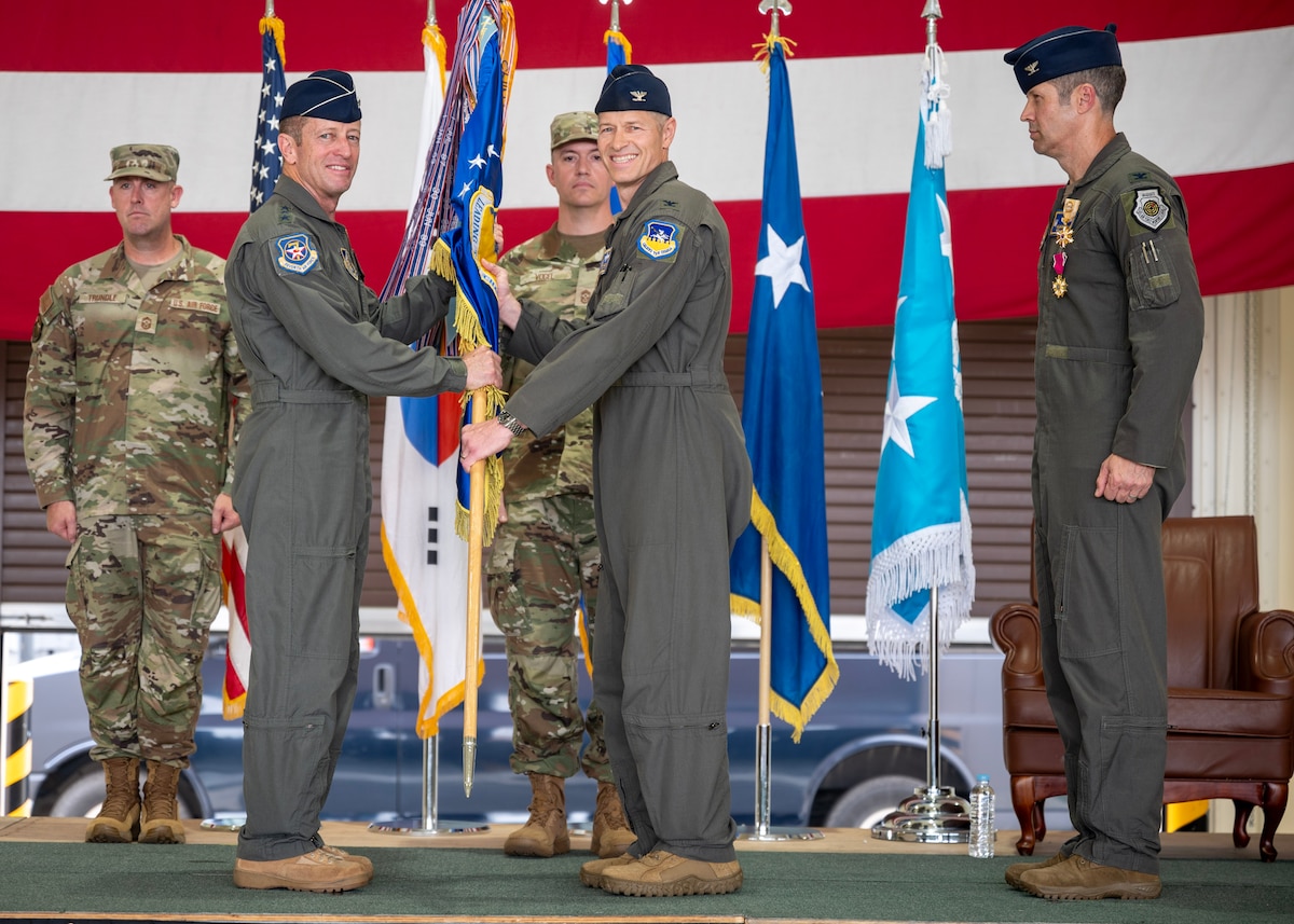 U.S. Air Force Col. Ryan Ley, center, incoming 51st Fighter Wing commander,  accepts command of the 51st FW from Lt. Gen. David Iverson, left, Seventh Air Force commander, during a Change of Command ceremony at Osan Air Base, Republic of Korea, June 27, 2025. Prior to assuming command, Ley served as the deputy commander of the 52nd FW at Spangdahlem, Germany. (U.S. Air Force photo by Staff Sgt. Sarah Williams)