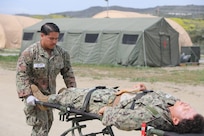 Hospital Apprentice Juan Casassanchez, moves Equipment Operator Constructionman Hayden Hernandez, a casualty role player, Naval Mobile Construction Battalion FIVE (NMCB-5), on a litter during training at Naval Expeditionary Medicine Warfighter Development Center (NEMWDC) May 3-16. (U.S. Navy photo by Petty Officer 2nd Class Kwame Obengyeboah)