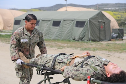 Hospital Apprentice Juan Casassanchez, moves Equipment Operator Constructionman Hayden Hernandez, a casualty role player, Naval Mobile Construction Battalion FIVE (NMCB-5), on a litter during training at Naval Expeditionary Medicine Warfighter Development Center (NEMWDC) May 3-16. (U.S. Navy photo by Petty Officer 2nd Class Kwame Obengyeboah)