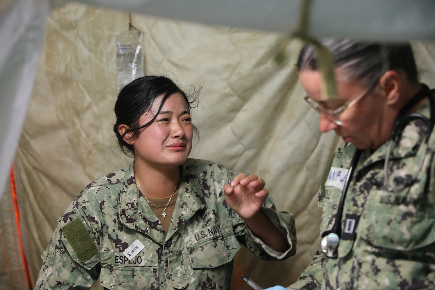 Equipment Operator Nemilyn Espejo (left), Naval Mobile Construction Battalion FIVE (NMCB-5), portrays a patient experiencing nausea and vomiting is evaluated by physician assistant Lt. Megan Doll (right) from Expeditionary Medical Facility Juliet (EMF-J) during EMF training at Naval Expeditionary Medicine Warfighter Development Center (NEMWDC) May 3-16, 2025. Simulated clinical scenarios help medical personnel practice triage and treatment in realistic operational settings. (U.S. Navy photo by Petty Officer 2nd Class Kwame Obengyeboah)
