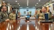 Airmen sit around a conference table for a briefing.