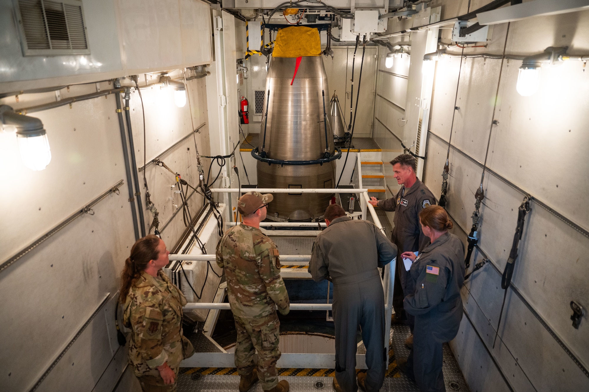 A group of Airmen look around the inside of Uniform-01's payload transporter.