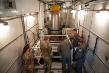A group of Airmen look around the inside of Uniform-01's payload transporter.