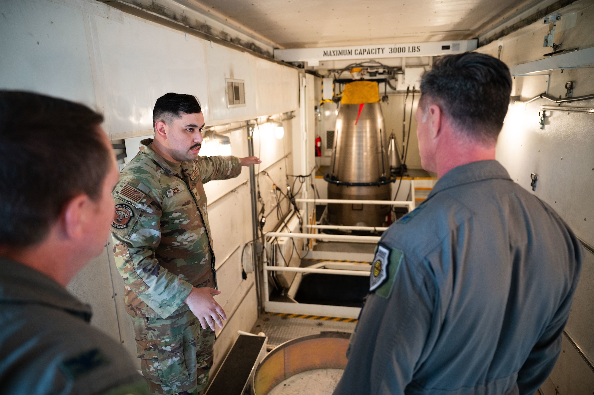 A missile maintenance team Airman shows around the interior of a payload transporter.
