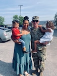 Soldier posing with his wife and two children.