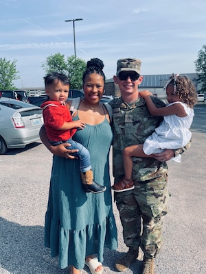 Soldier posing with his wife and two children.