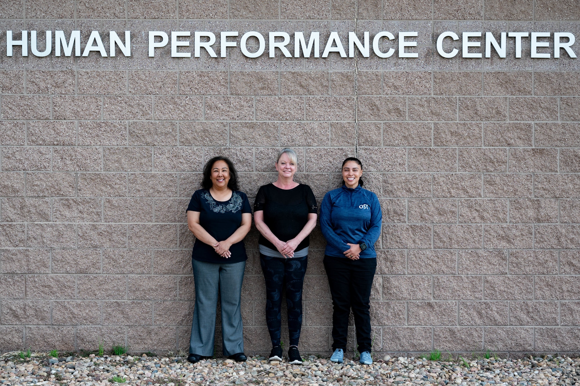 three women standing in front of a wall posing for photo