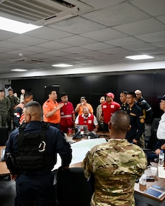 A member from the exercise crisis response team addresses a group working on the emergency response plan during a training scenario.
