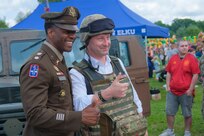 U.S. Army Lt. Col. William Branch, Multinational Battle Group Poland commander, 1st Armored Division, 3rd Infantry Division, supporting Task Force Iron, poses for a photo with Tomasz Andrukiewicz, mayor of Ełk, near a static display of military vehicles during the city’s 600th anniversary celebration, May 31, 2025. Soldiers from the United States, Romania, and the United Kingdom joined residents in celebrating the jubilee milestone. The event allowed residents to interact directly with soldiers from Battle Group Poland, fostering relationships and building cultural understanding. Task Force Iron’s mission is to engage in multinational training and exercises across the continent to increase lethality while strengthening partnerships with NATO allies and regional security partners. The task force provides combat-credible forces to V Corps, America’s only forward-deployed corps in Europe.