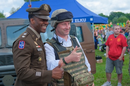 U.S. Army Lt. Col. William Branch, Multinational Battle Group Poland commander, 1st Armored Division, 3rd Infantry Division, supporting Task Force Iron, poses for a photo with Tomasz Andrukiewicz, mayor of Ełk, near a static display of military vehicles during the city’s 600th anniversary celebration, May 31, 2025. Soldiers from the United States, Romania, and the United Kingdom joined residents in celebrating the jubilee milestone. The event allowed residents to interact directly with soldiers from Battle Group Poland, fostering relationships and building cultural understanding. Task Force Iron’s mission is to engage in multinational training and exercises across the continent to increase lethality while strengthening partnerships with NATO allies and regional security partners. The task force provides combat-credible forces to V Corps, America’s only forward-deployed corps in Europe.
