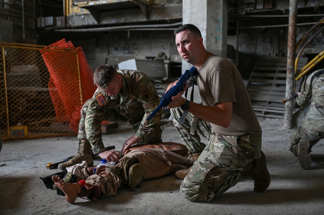 U.S. Air Force Staff Sgt. John Paget III, 445th Aeromedical Staging Squadron medical technician, provides security as a fellow U.S. Soldier provides medical care to a simulated patient for Tactical Combat Casualty Care training during Exercise Relentless Valor at Wright State University's Calamityville, Fairborn, Ohio, June 6, 2025. Calamityville is a training, testing and research venue where military and civilian emergency first responders hone their skills while building relationships. The exercise was designed to enhance the joint force’s ability to maneuver and conduct missions in contested, degraded and operationally limited environments. (U.S. Air Force photo by Master Sgt. Patrick OReilly)