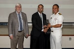 Three gentlemen stand together holding an award