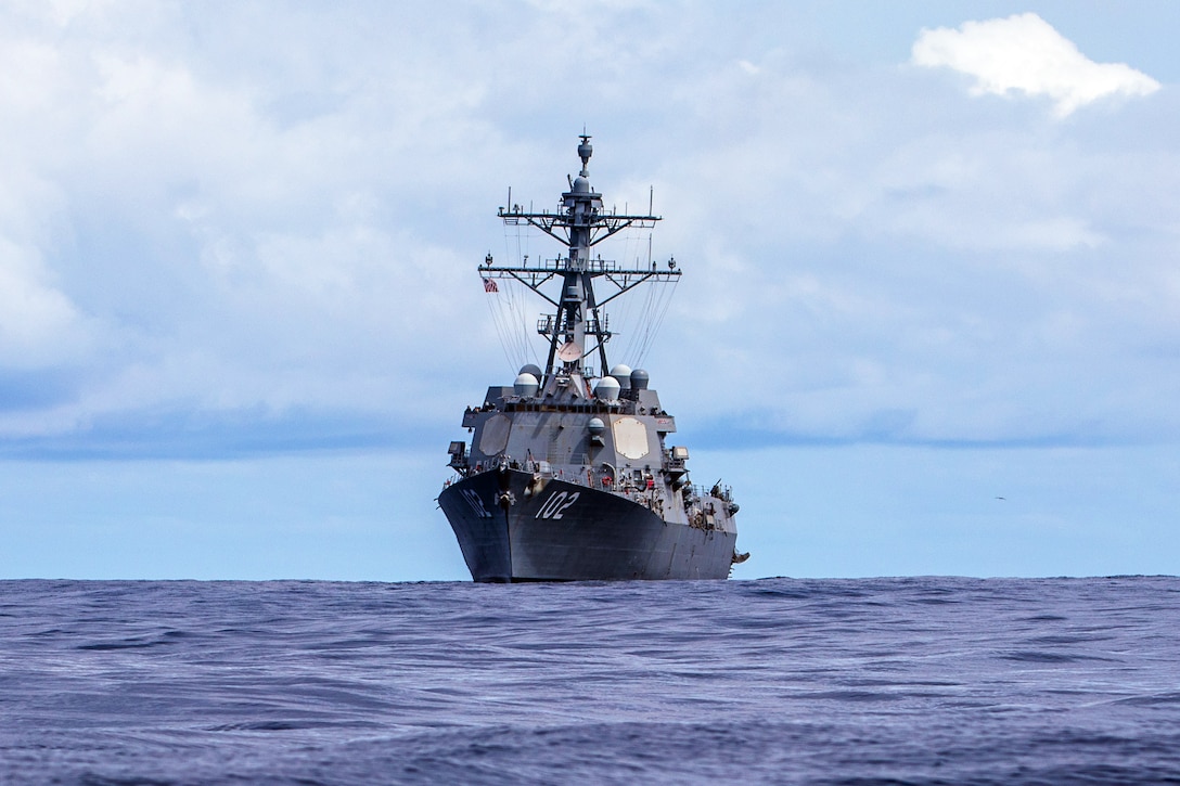 A military ship cruises in the ocean on a cloudy day.