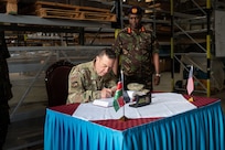 U.S. Air Force Maj. Gen. Gary Keefe, the adjutant general of the Massachusetts National Guard (MANG), signs a book beside Kenya Defence Forces (KDF) Lt. Gen. D K C Tarus, the commander of the Kenya Army, during his visit to the Kahawa Barracks in Nairobi, Kenya, May 30, 2025.