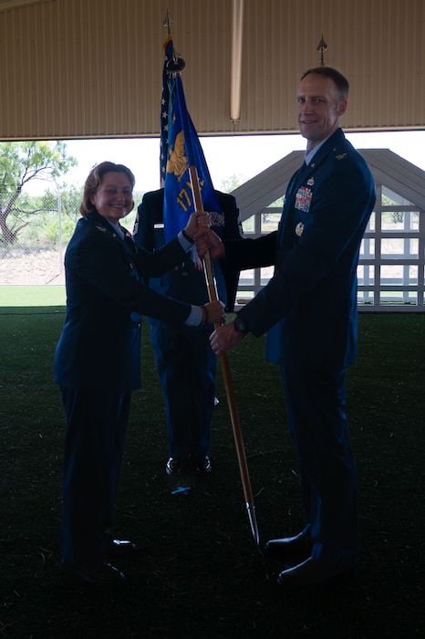 U.S. Air Force Col. Angelina Maguinness, 17th Training Wing commander, passes the guidon to Col. Nathan Olsen, 17th Mission Support Group commander, during the change of command ceremony at the 17th Security Forces Squadron kennels, Goodfellow Air Force Base, Texas, June 26, 2025. The passing of the guidon is a military tradition that dates back to the time of Frederick the Great of Prussia. (U.S. Air Force photo by Airman 1st Class Brian Lummus)