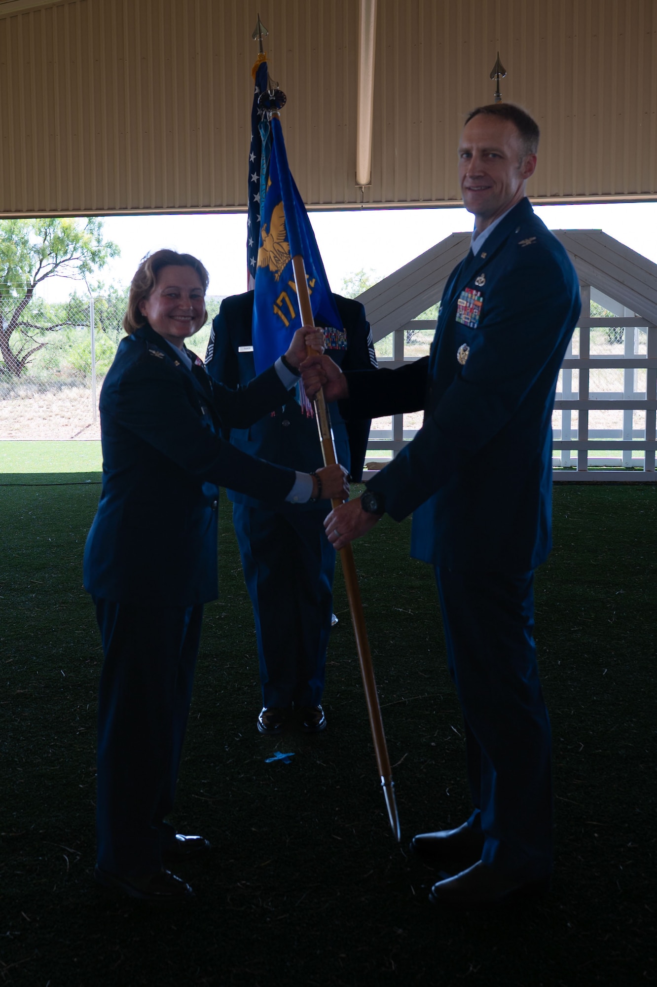 U.S. Air Force Col. Angelina Maguinness, 17th Training Wing commander, passes the guidon to Col. Nathan Olsen, 17th Mission Support Group commander, during the change of command ceremony at the 17th Security Forces Squadron kennels, Goodfellow Air Force Base, Texas, June 26, 2025. The passing of the guidon is a military tradition that dates back to the time of Frederick the Great of Prussia. (U.S. Air Force photo by Airman 1st Class Brian Lummus)
