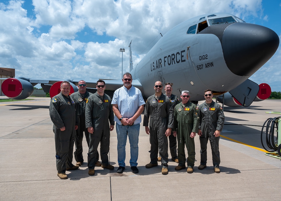 group poses for photo in front of aircraft