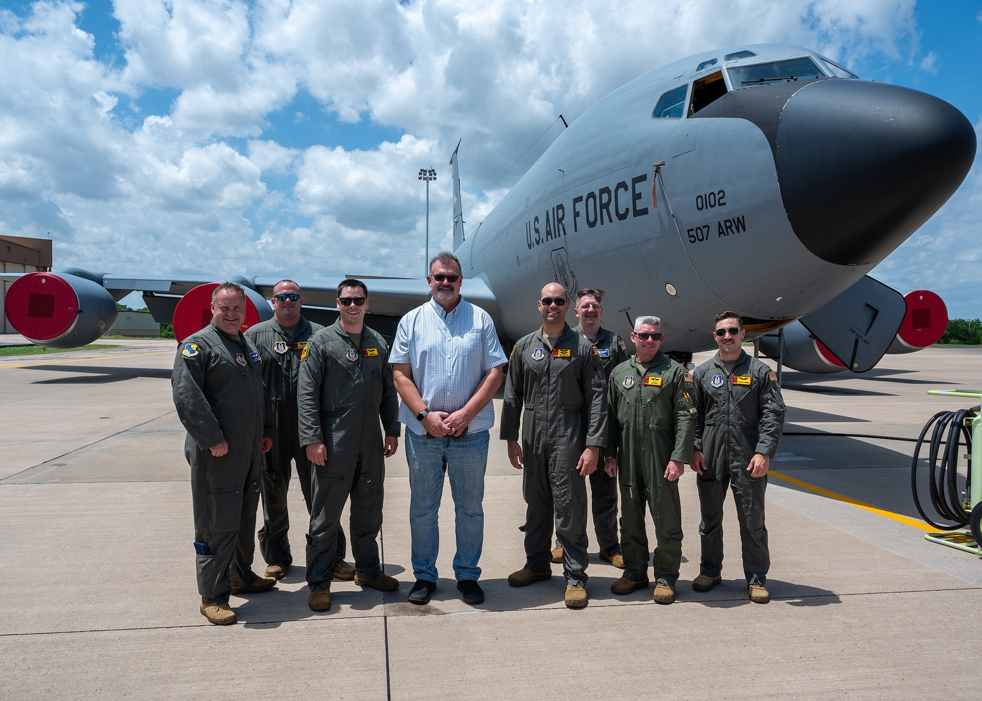 group poses for photo in front of aircraft