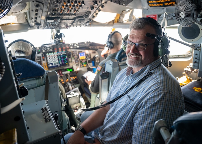 man poses for photo in cockpit of aircraft
