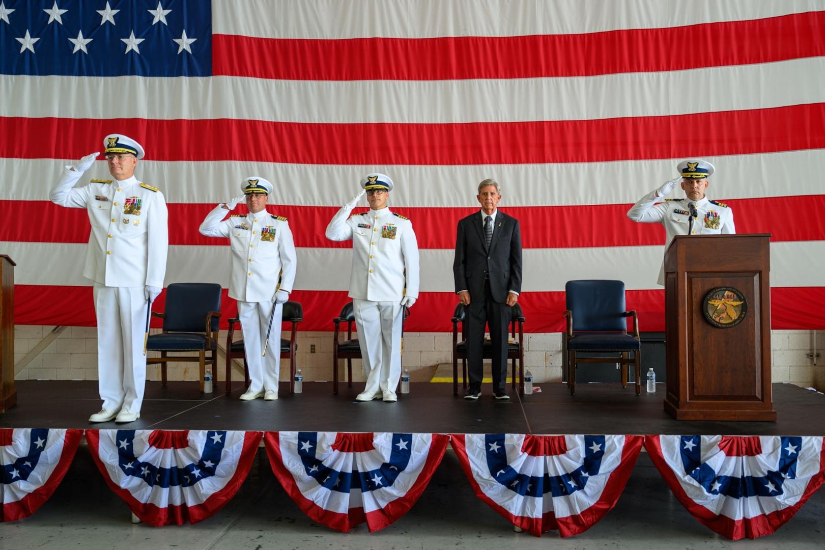 Rear Adm. Douglas Schofield (left), Seventh Coast Guard District commander, Capt. Eric Smith (second from left), former Air Station Miami commander, and Capt. Aaron Ortenzio (middle), Air Station Miami commander, render a salute during a change of command ceremony at Coast Guard Air Station Miami, June 27, 2025. During the ceremony Schofield presided as Ortenzio relieved Smith as the commander of Air Station Miami. (U.S. Coast Guard photo by Auxiliarist Joey Feldman)