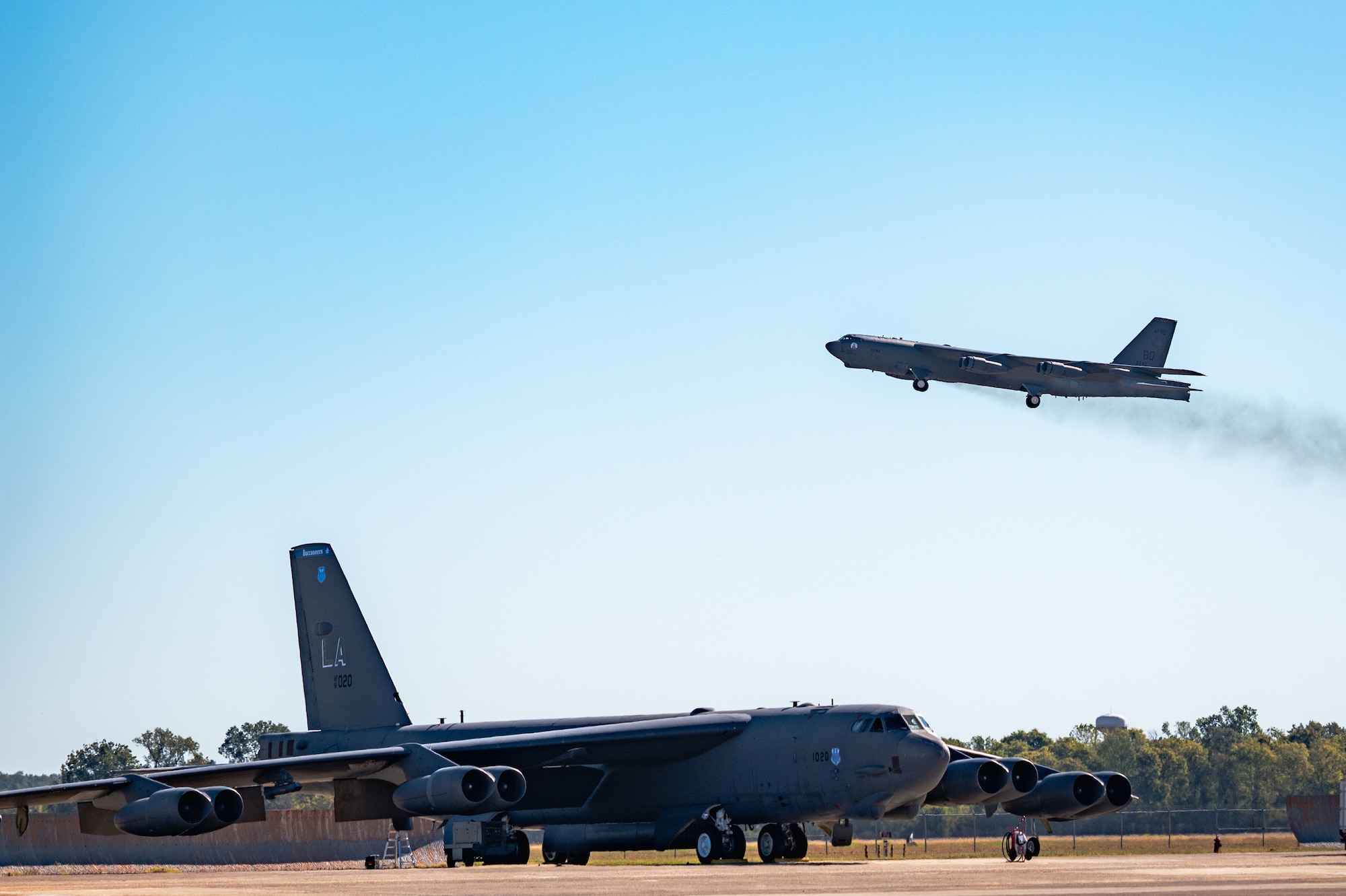 B-52 on the runway with another B-52 taking off in the background