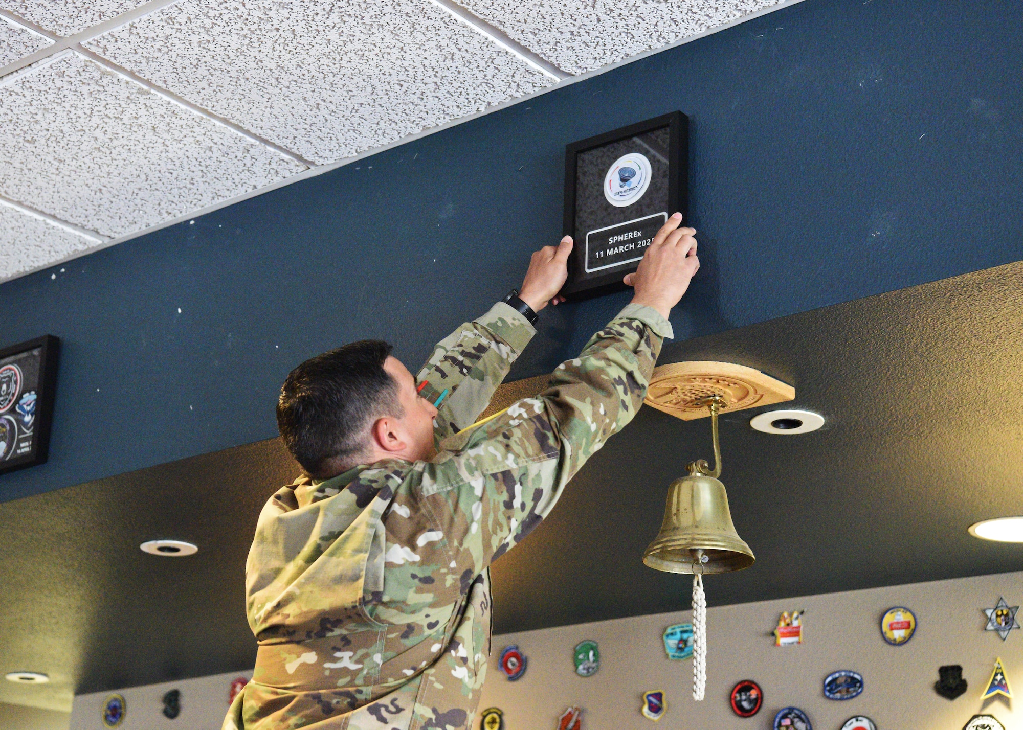 U.S. Space Force Lt. Col. Ralph Salazar, 2nd Range Operations Squadron commander, hangs a mission patch celebrating the recent launch of NASA SPHEREx at Vandenberg Space Force Base, Calif., June 26, 2025. NASA’s SPHEREx, launched March 11, 2025, with an objective to survey distant galaxies. The Space Force’s collaboration with NASA continues to embolden the United State’s presence in the space domain.