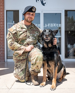 An Airman kneels with a MWD