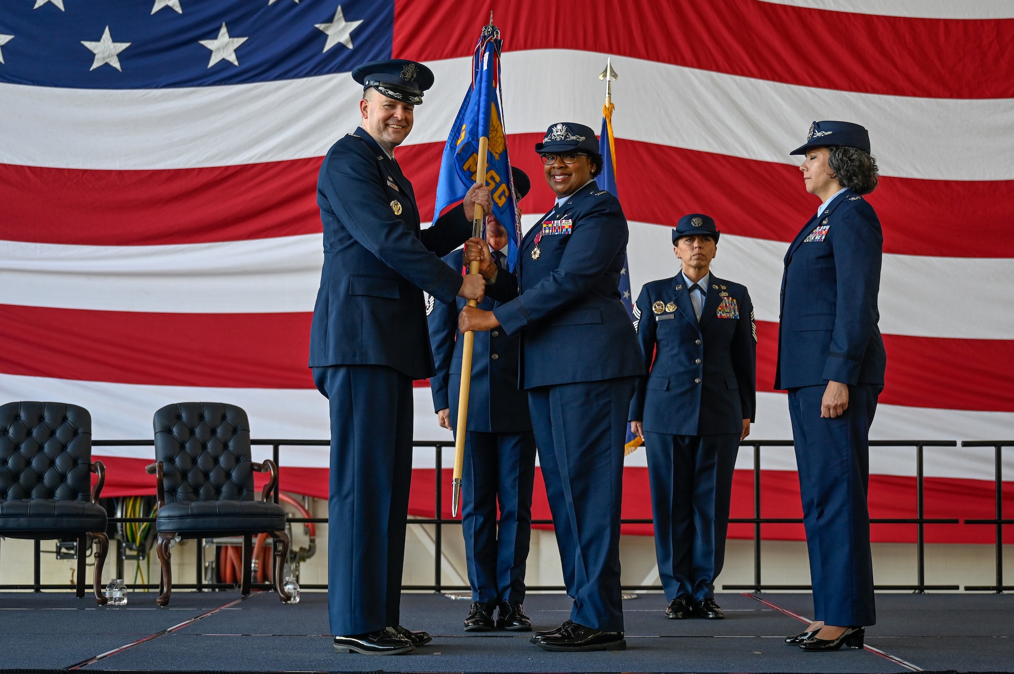 U.S. Air Force Col. N’Keiba Estelle, 19th Mission Support Group outgoing commander, passes the guidon to Col. Denny Davies (left), 19th Airlift Wing and installation commander, during a change of command ceremony, June 27, 2025, at Little Rock Air Force Base, Arkansas.