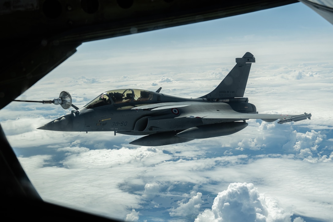 An aircraft flies above clouds as seen from another aircraft.