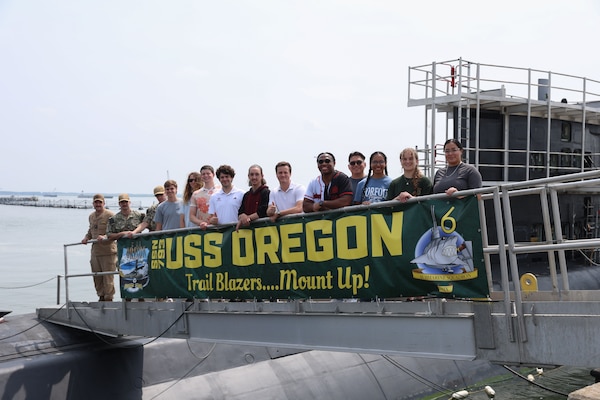 College student pose for a photo on the brow of USS Oregon