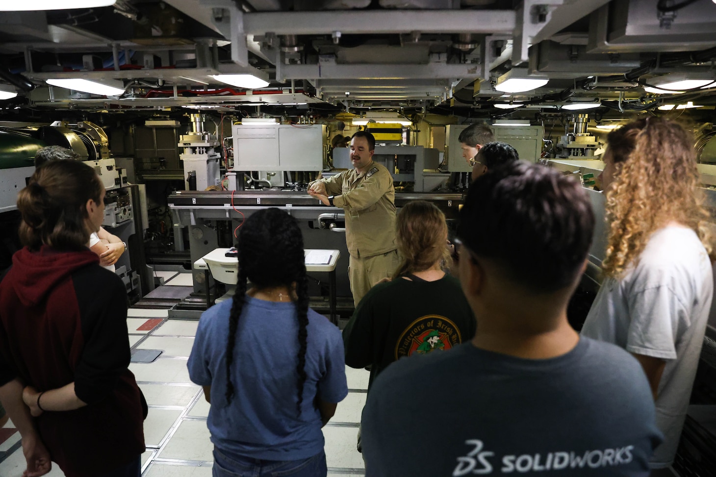 College students listen to a Submariner explain the different functions of the vessel during a tour of USS Oregon.