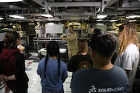 College students listen to a Submariner explain the different functions of the vessel during a tour of USS Oregon.