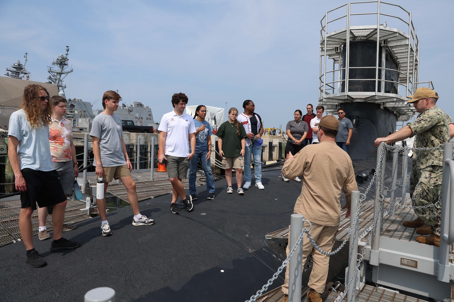 College students listen to a Submariner explain the different functions of the vessel during a tour of USS Oregon.