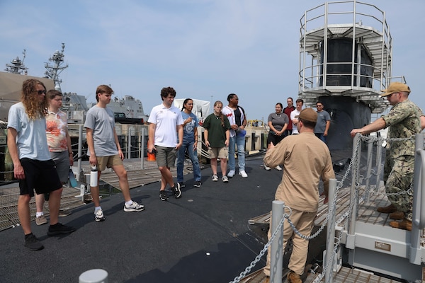 College students listen to a Submariner explain the different functions of the vessel during a tour of USS Oregon.